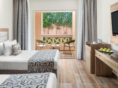 Modernes Hotelzimmer mit zwei Betten, Holzfußboden, großem Fenster und Fernseher an der Wand.