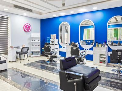 Salón de peluquería moderno con paredes azules, espejos y sillas negras.