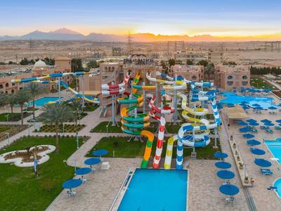 Grand parc aquatique avec plusieurs toboggans colorés et plusieurs piscines dans une station hôtelière au coucher du soleil.