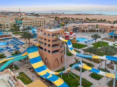 Grand complexe avec toboggans aquatiques, piscines et nombreux bâtiments au bord de la mer.