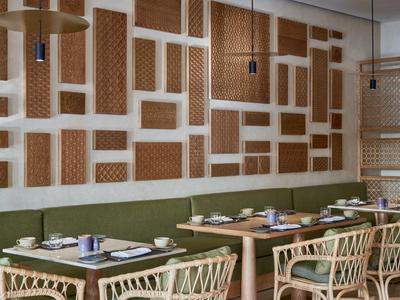 Restauracja z wiklinowymi krzesłami, serwetkami i dekoracyjnymi ścianami w brązowo-białych kolorach.