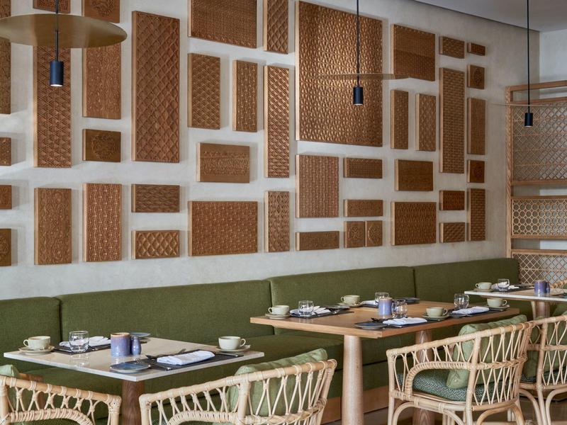 Restauracja z wiklinowymi krzesłami, serwetkami i dekoracyjnymi ścianami w brązowo-białych kolorach.