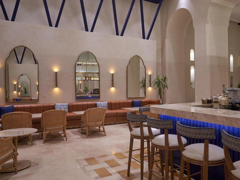 Elegancki salon hotelowy z podświetlanym barem i wygodnymi siedzeniami pod białymi łukami.