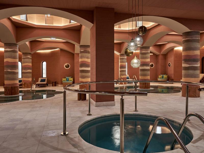 Eleganckie spa z okrągłymi basenami, dekoracyjnymi kolumnami i ciepłymi kolorami ścian.