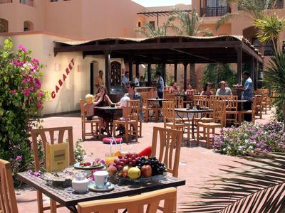 Area esterna dell'hotel con tavoli, sedie e pasti apparecchiati sotto il sole