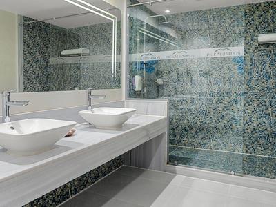 Bagno moderno con doppio lavabo e doccia con porte in vetro.