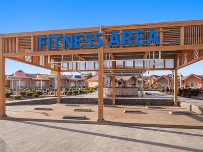 Grande zone de fitness en plein air avec structure en bois et ciel bleu en arrière-plan.