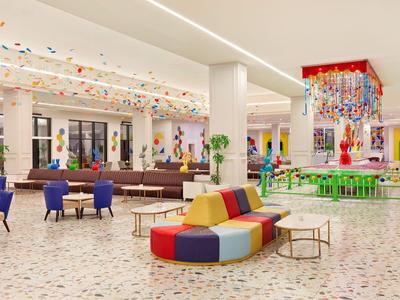 Grande hall d'hotel con sedute colorate e decorazioni festive.