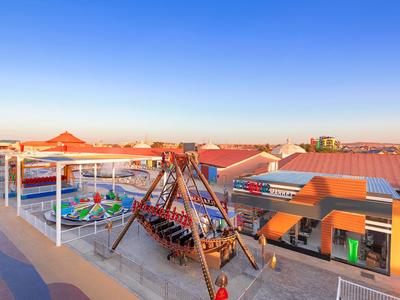 Terrasse sur le toit avec aire de jeux et vue sur les bâtiments sous un ciel bleu au coucher du soleil.