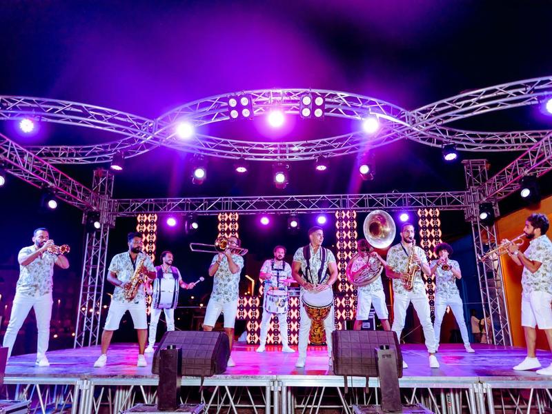 Spettacolo colorato sul palco con una band che suona strumenti a fiato di notte