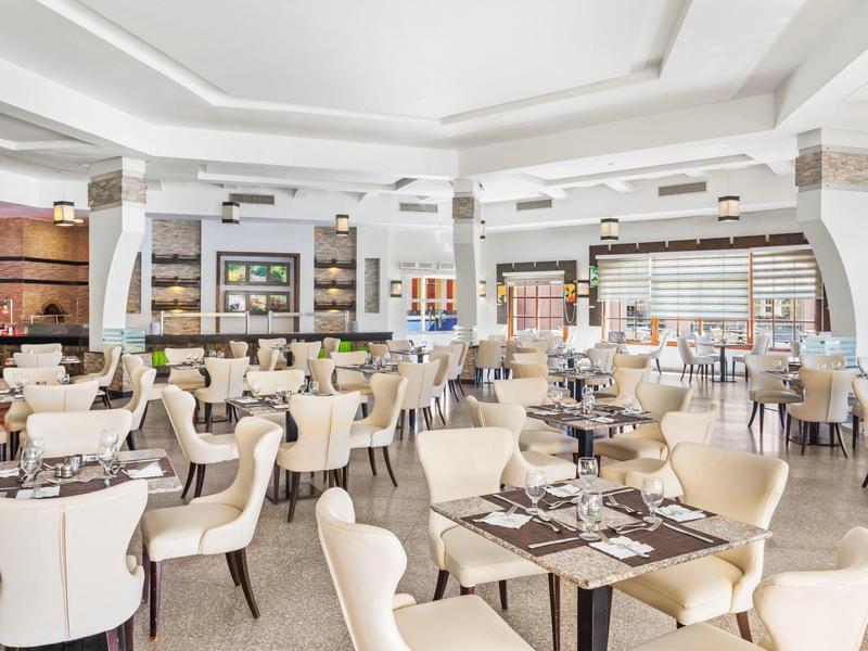 Ampia sala da pranzo moderna con sedie chiare e tavoli scuri in un hotel.