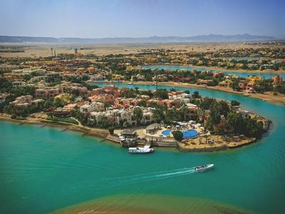 Luchtfoto van een eiland met hotels omgeven door turquoise water en een boot op de waterweg.