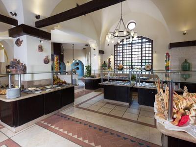 Przestronna strefa bufetu hotelowego z pieczywem, ciastami i eleganckimi detalami architektonicznymi.