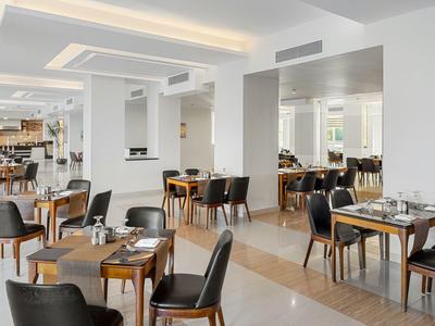 Nowoczesna jadalnia hotelowa z drewnianymi stołami i czarnymi krzesłami.