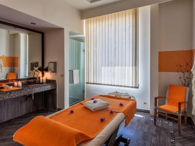 Cozy massage room with orange blankets and chair, warm lighting, and modern design.