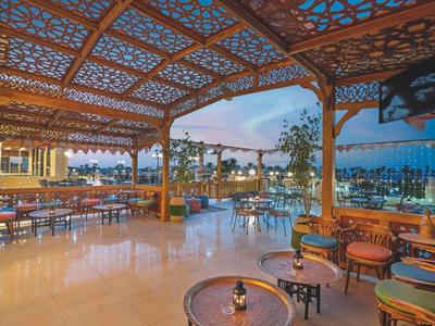Open covered terrace with carved wood and view of a pool at dusk.