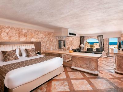 Luksusowy pokój hotelowy z dużym łóżkiem, marmurową podłogą i tarasem z widokiem na morze.