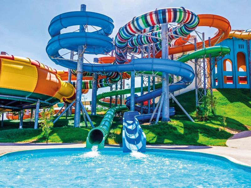 Parc aquatique avec toboggans colorés et piscine bleue sous un ciel clair.