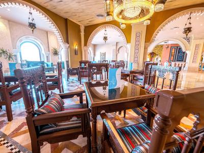 Elegantes Hotelrestaurant mit Holzmöbeln, bunten Kissen und dekorativen Bögen.