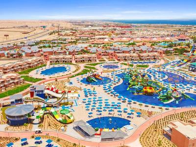 Großer Wasserpark mit Pools, Wasserrutschen, Sonnenschirmen und Liegestühlen in Wüstenumgebung.