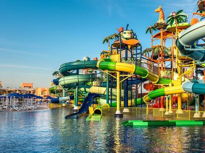 Bunter Wasserpark mit Rutschen und Palmen am Wasser bei klarem Himmel