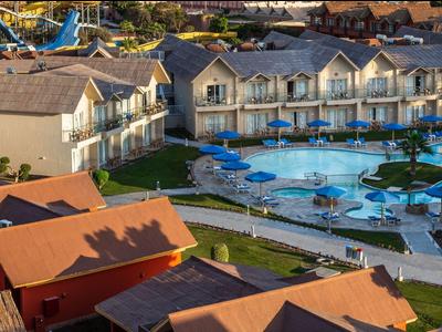 Blick auf ein Hotelgelände mit Pools, Sonnenschirmen und Gebäuden unter warmem Licht.