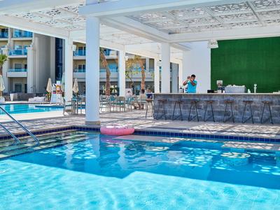 Piscine extérieure moderne avec bar et places assises sous un auvent blanc.