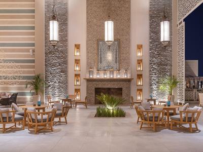 Elegancki taras hotelowy z drewnianymi stolikami, krzesłami i centralnym kominkiem pod wiszącymi lampami.