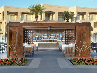 Nowoczesny zewnętrzny obszar hotelowy z barem, miejscami do siedzenia i ozdobnym drewnianym łukiem.