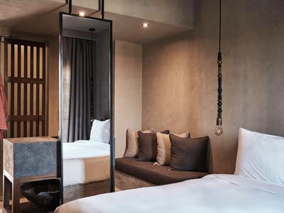 Modernes Hotelzimmer mit großem Bett, Sofa, Spiegel und elegantem Lichtdesign.