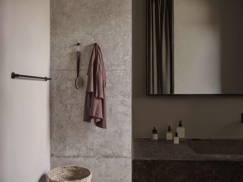 Modernes Badezimmer mit grauer Wand, Handtuch und Spiegel über Steinwaschbecken.