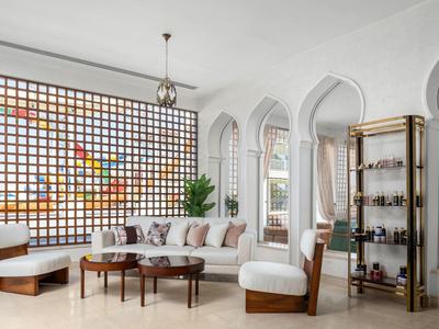 Eleganter Hotel-Loungebereich mit weißen Sesseln, Holztischen und dekorativen Bögen an der Wand.