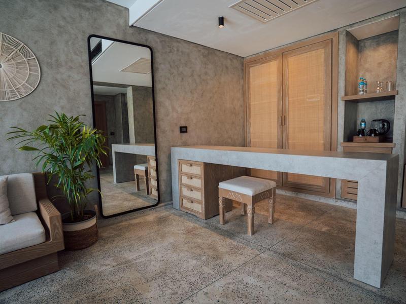 Angolo scrivania in hotel con grande specchio, divano e pianta verde.