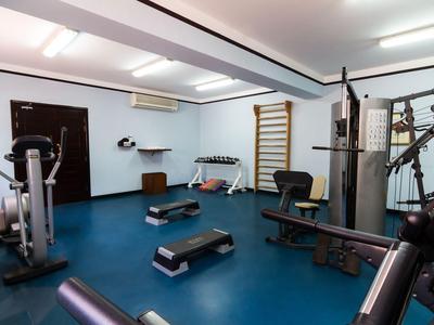 Moderner Fitnessraum mit Trainingsgeräten auf blauem Boden in einem hellen Raum.