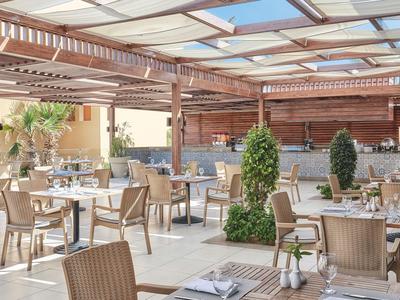 Modernes, luftiges Restaurant mit Holzakzenten und bequemen Stühlen unter einem transparenten Dach.