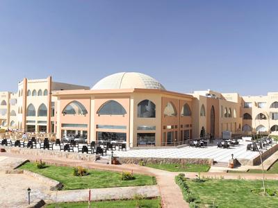 Duży budynek hotelu z jasnymi ścianami, łukami i białą kopułą pod czystym niebem