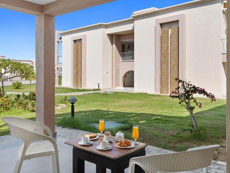 Terrazza con colazione e vista su prato e edificio moderno.