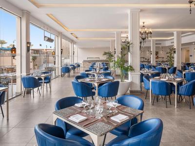 Restaurante moderno y luminoso con sillas azules y elegantes cubiertos.