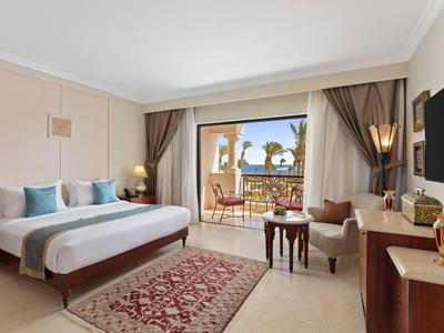 Habitación de hotel moderna con cama doble, alfombra, escritorio y balcón con vistas al mar.