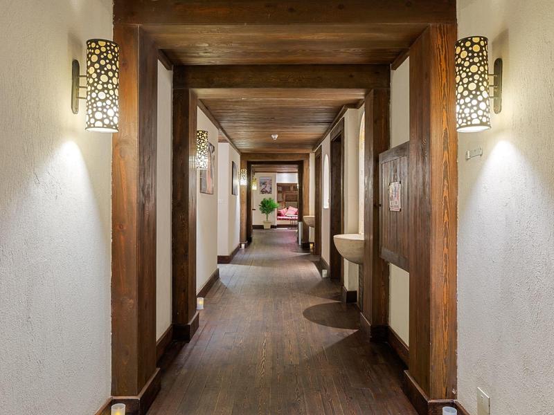 Corridoio d'hotel in legno con illuminazione soffusa e arredamento moderno.
