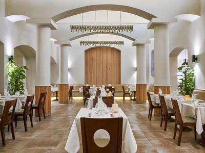 Ristorante elegante con tovaglie bianche, mobili in legno e colonne bianche in un ambiente luminoso.