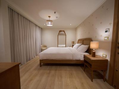 Modern eingerichtetes Hotelzimmer mit Doppelbett, Nachttischlampen und Holzboden.