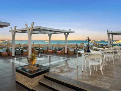 Rooftop terrace with seating areas and fire pit at sunset overlooking the sea.