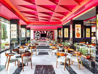 Ristorante moderno con motivo geometrico sul soffitto e mobili in legno eleganti sotto luce rossa.