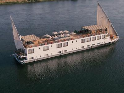 Modern riviervormig woonboot met grote ramen op kalm water.