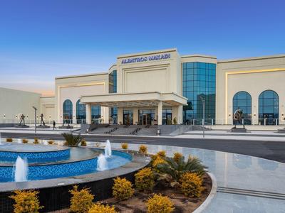 Grand bâtiment d'hôtel avec fontaine et jardin paysager au premier plan.