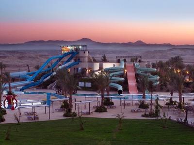 Een groot waterpark met zwembaden en glijbanen bij zonsondergang.