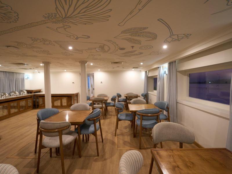 Modern, helder restaurant met houten vloeren en meerdere tafels en stoelen.