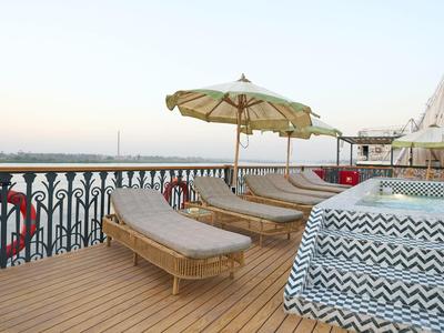Terrazza sul tetto con lettini, ombrellone e vista mare sotto cielo limpido.