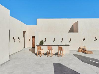 Moderner Innenhof mit weißen Wänden, Holztisch und Stühlen, klarem blauem Himmel, minimalistischem Design.